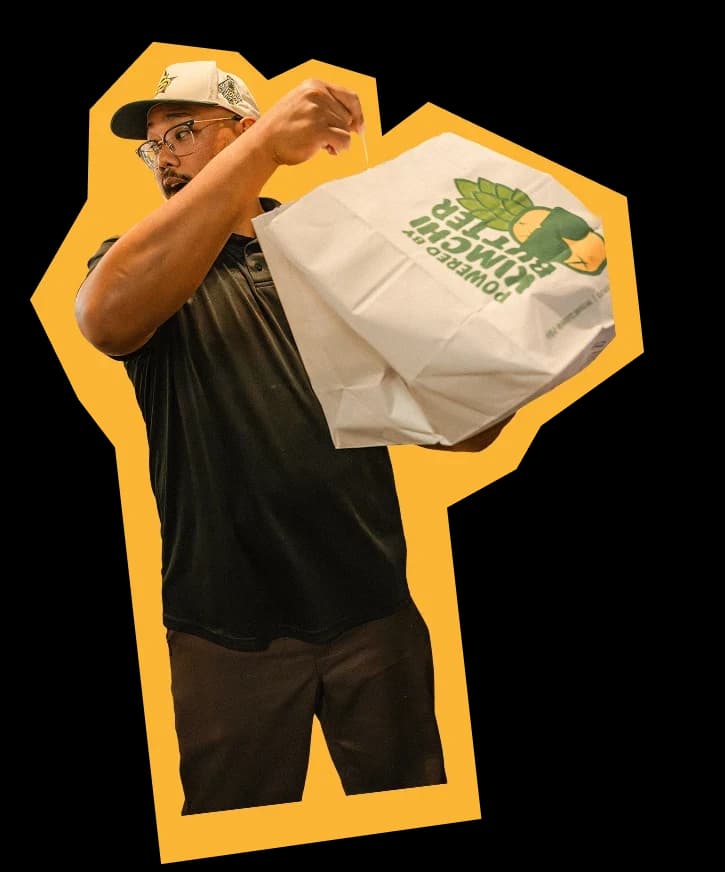 A crew member proudly holding up a Shootz takeout bag