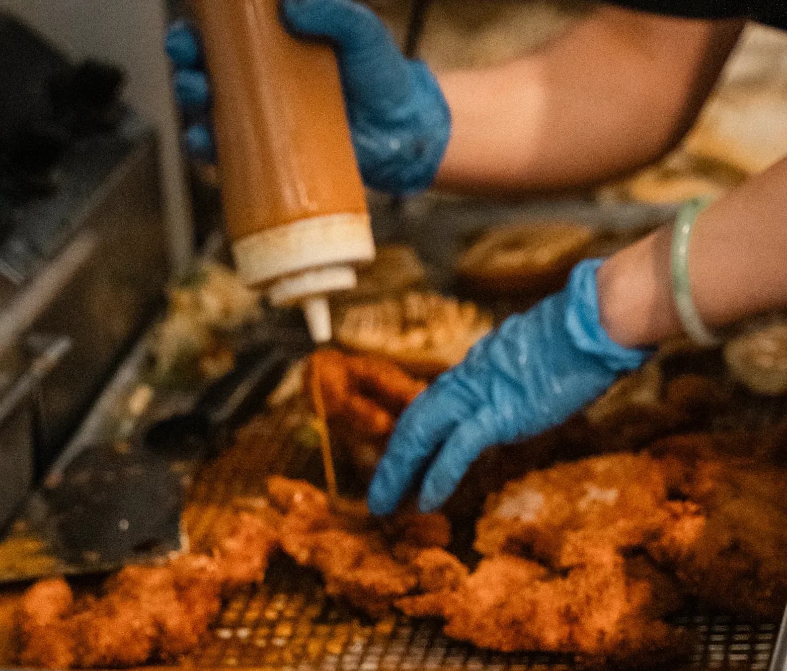 Sauce drizzled over fresh katsu on the fryer rack