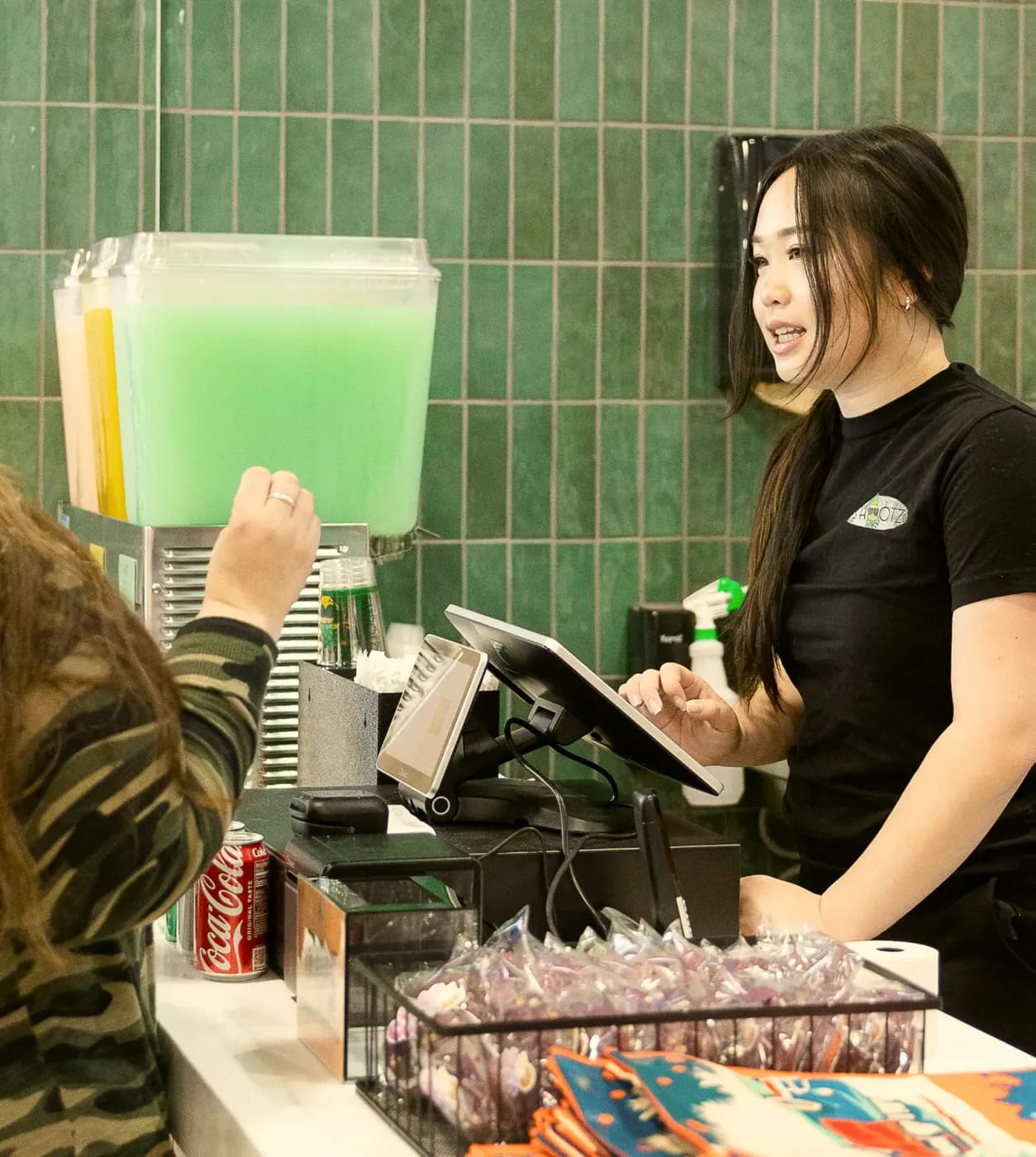 A Shootz crew member smiling while taking an order at the register