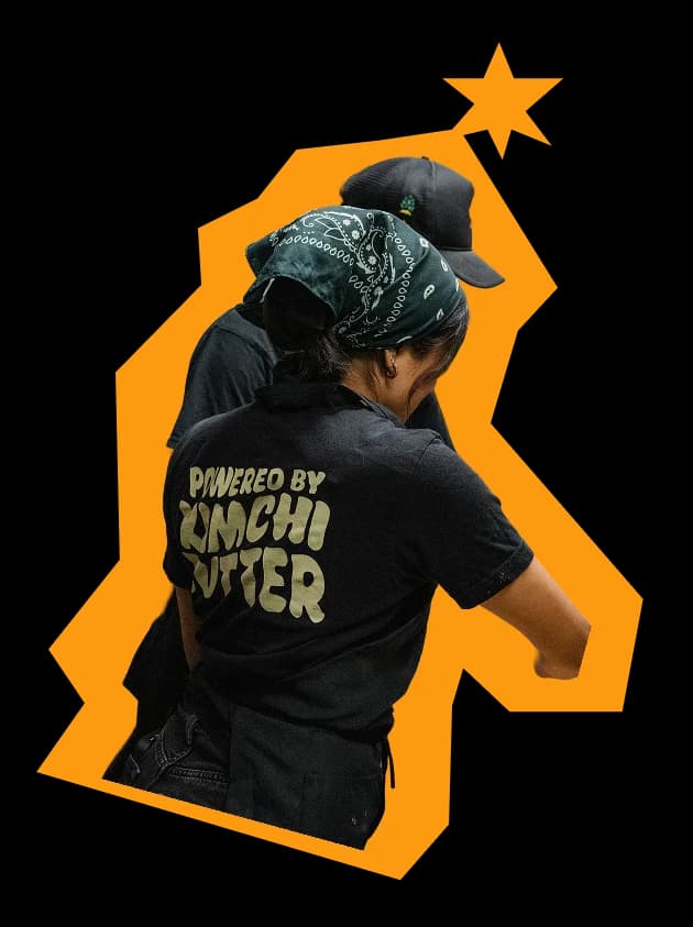 Two crew members working the line in Powered By Kimchi Butter shirts